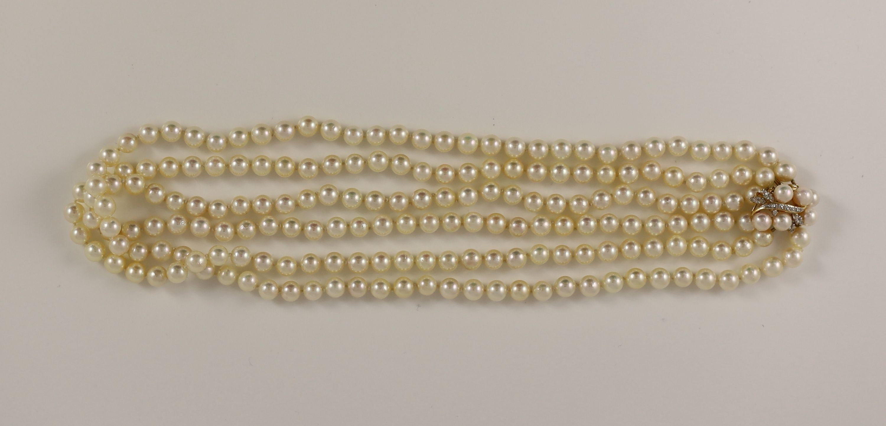 A modern triple strand cultured pearl necklace, with a 14k gold, cultured pearl and diamond set clasp